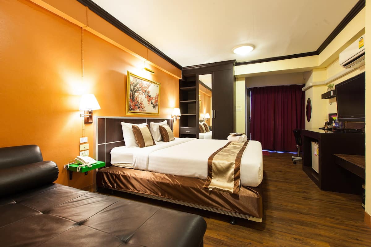 Ein Hotelzimmer mit einem großen Bett, einem Schreibtisch, einem Fernseher und einer Sitzecke.