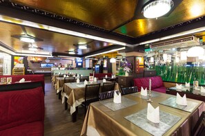 L'intérieur d'un restaurant, avec des banquettes et des tables, dont certaines sont équipées de menus et de serviettes.