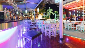 Een bar met een lange toonbank, diverse stoelen en tafels voor diners.