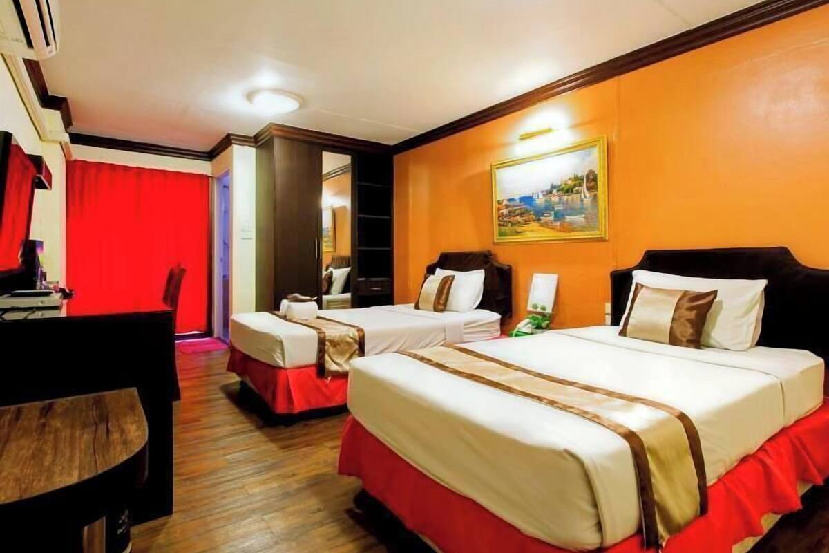 Ein Hotelzimmer mit zwei Betten, einem Schreibtisch und einem roten Vorhang.