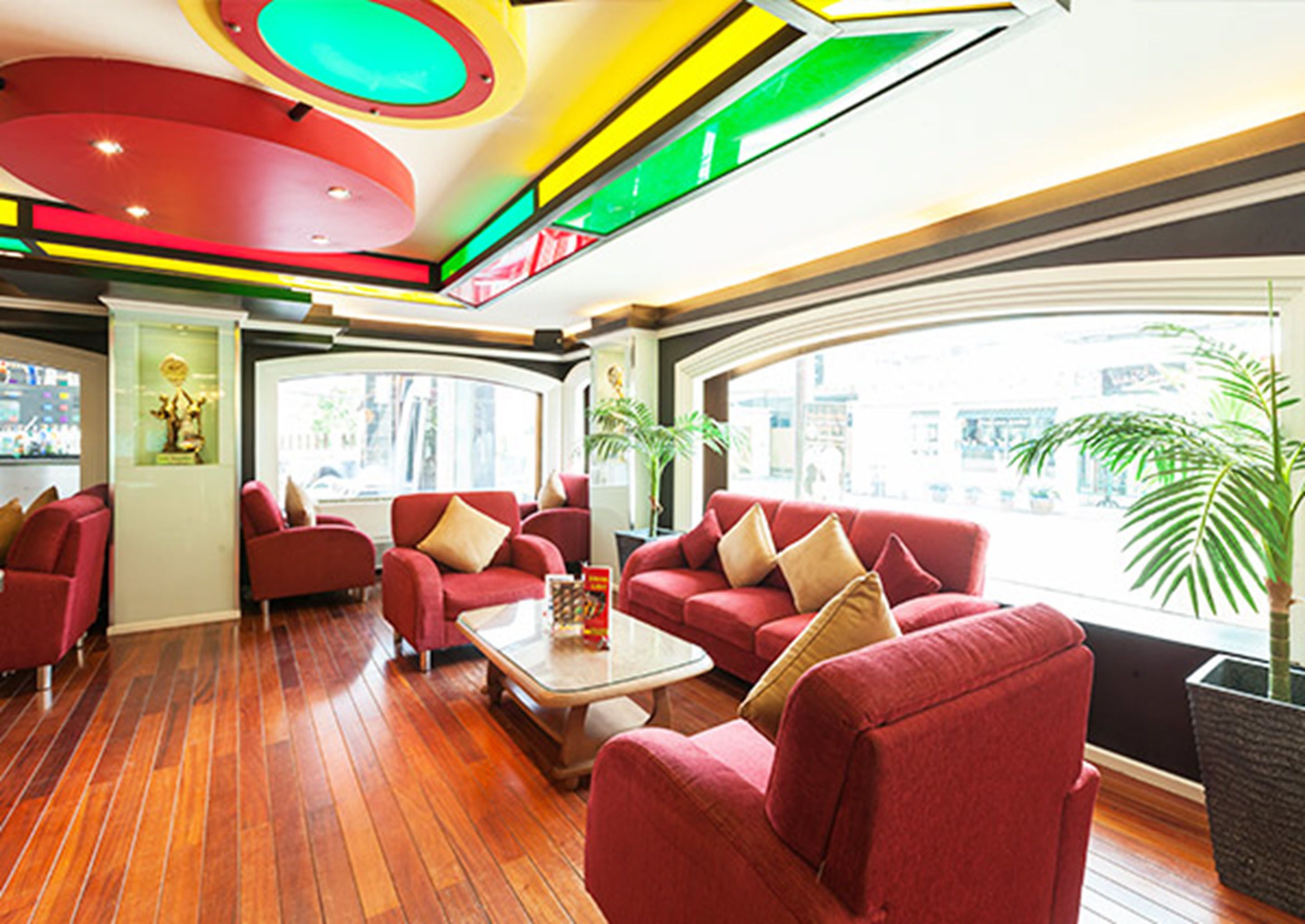 A modern interior with red sofas, a glass coffee table, and a large window offering a city view.