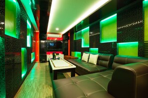 A modern lounge area with a sofa, a coffee table, and a TV screen. - Vabua Asotel Bangkok (Bangkok)