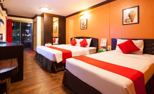 Une chambre d’hôtel avec deux lits, chacun doté d’une literie rouge et blanche, de têtes de lit en bois et d’un plancher en bois.