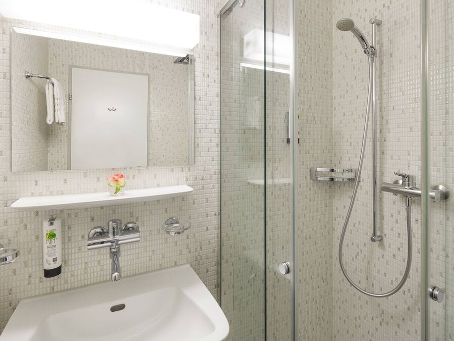 A modern bathroom with a glass-enclosed shower, a white sink, and a mirror above the sink.