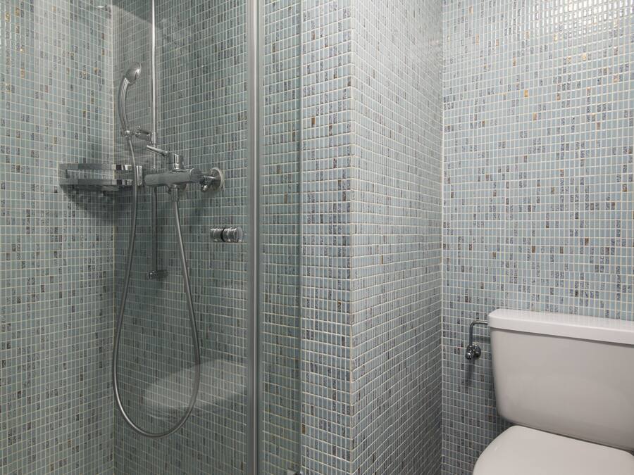 A bathroom with a glass-enclosed shower, a toilet, and tiled walls.