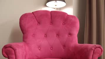 A pink tufted armchair with a high backrest and button details.