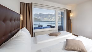 Ein Hotelzimmer mit zwei Betten, Meerblick und einem Balkon mit Sitzgelegenheiten.