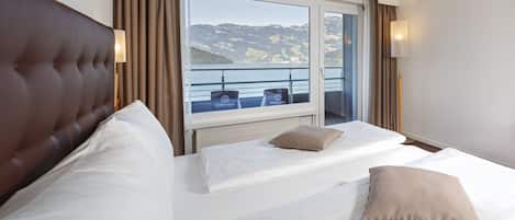 Habitación de hotel con dos camas, vista al mar y balcón con sillas.