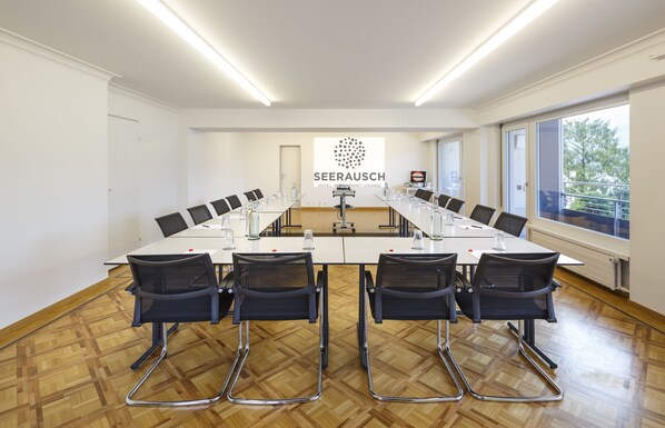 A conference room with a long table, chairs, and a logo on the wall. - Seerausch Swiss Quality Hotel (Beckenried)