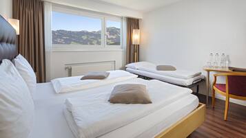 Une chambre d’hôtel avec deux lits, un bureau en bois et une vue sur les montagnes.