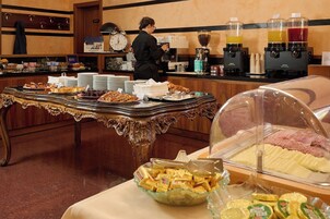 Montaje de bufé con diferentes opciones de comida, una estación de café y un reloj en la pared.