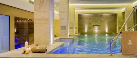 Un área de spa con piscina, columnas de mármol y un perchero para toallas.