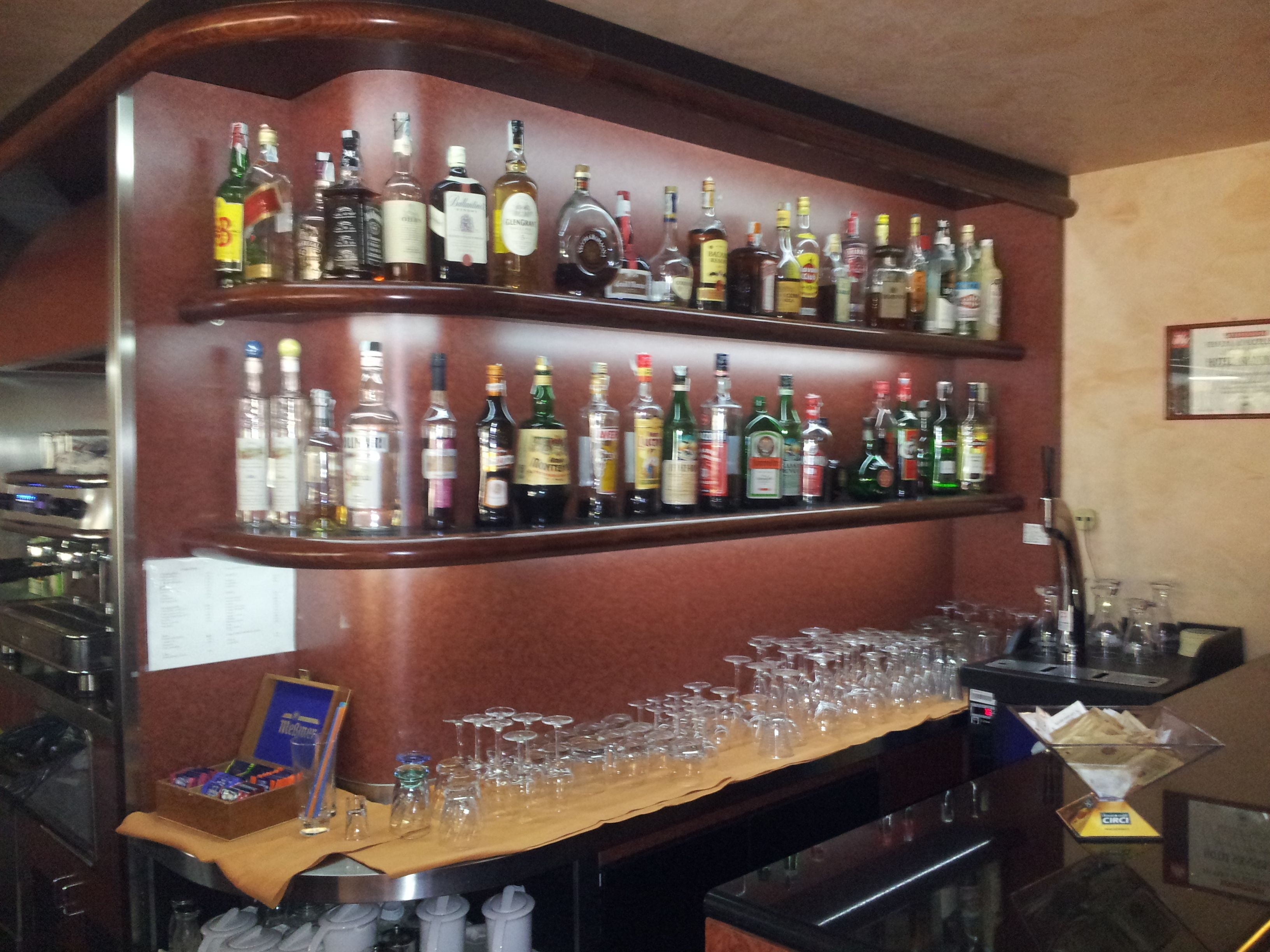 A bar area with multiple shelves of liquor bottles and a bar counter with glasses and bottles.