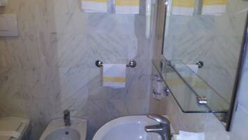 Une salle de bain équipée d’un bidet, d’un lavabo et d’un miroir.