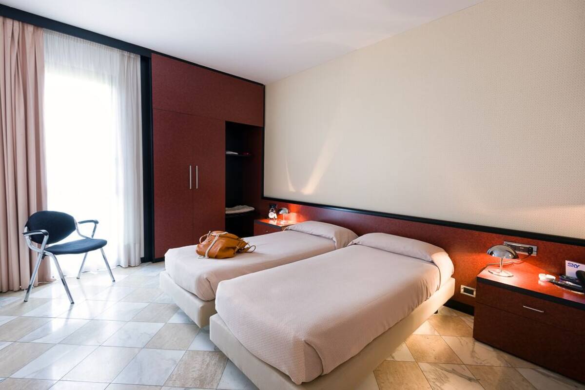 Een hotelkamer met twee bedden, een stoel, een bureau en een kledingkast.