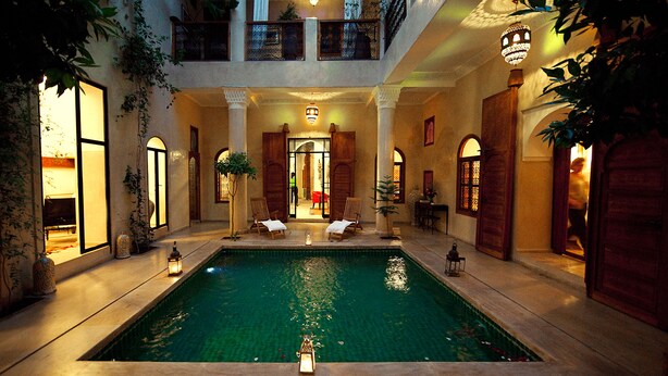 Una piscina interior lujosa con varios niveles, iluminación elegante y zonas de estar cómodas.