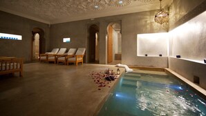 Un cuarto de spa con piscina, sillones de descanso y un techo decorativo.