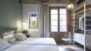 A bedroom with two beds, a wardrobe, a chair, and a window with curtains. - AinB Gothic-Jaume I Apartments (Barcelona)