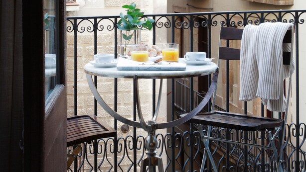 A balcony with a round table, chairs, and a potted plant. - AinB Gothic-Jaume I Apartments (Barcelona)