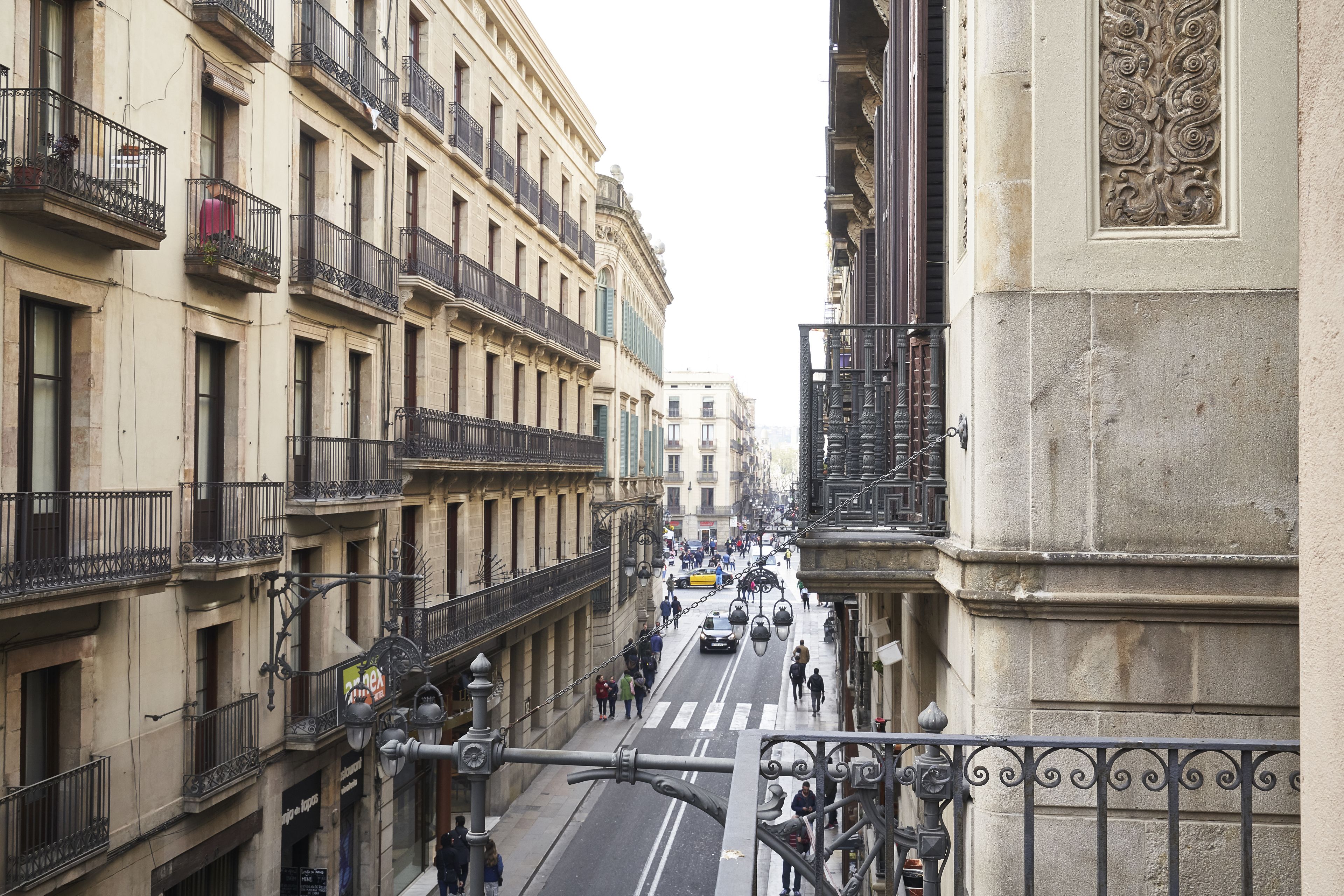 A street view with buildings, balconies, and a pedestrian crossing.