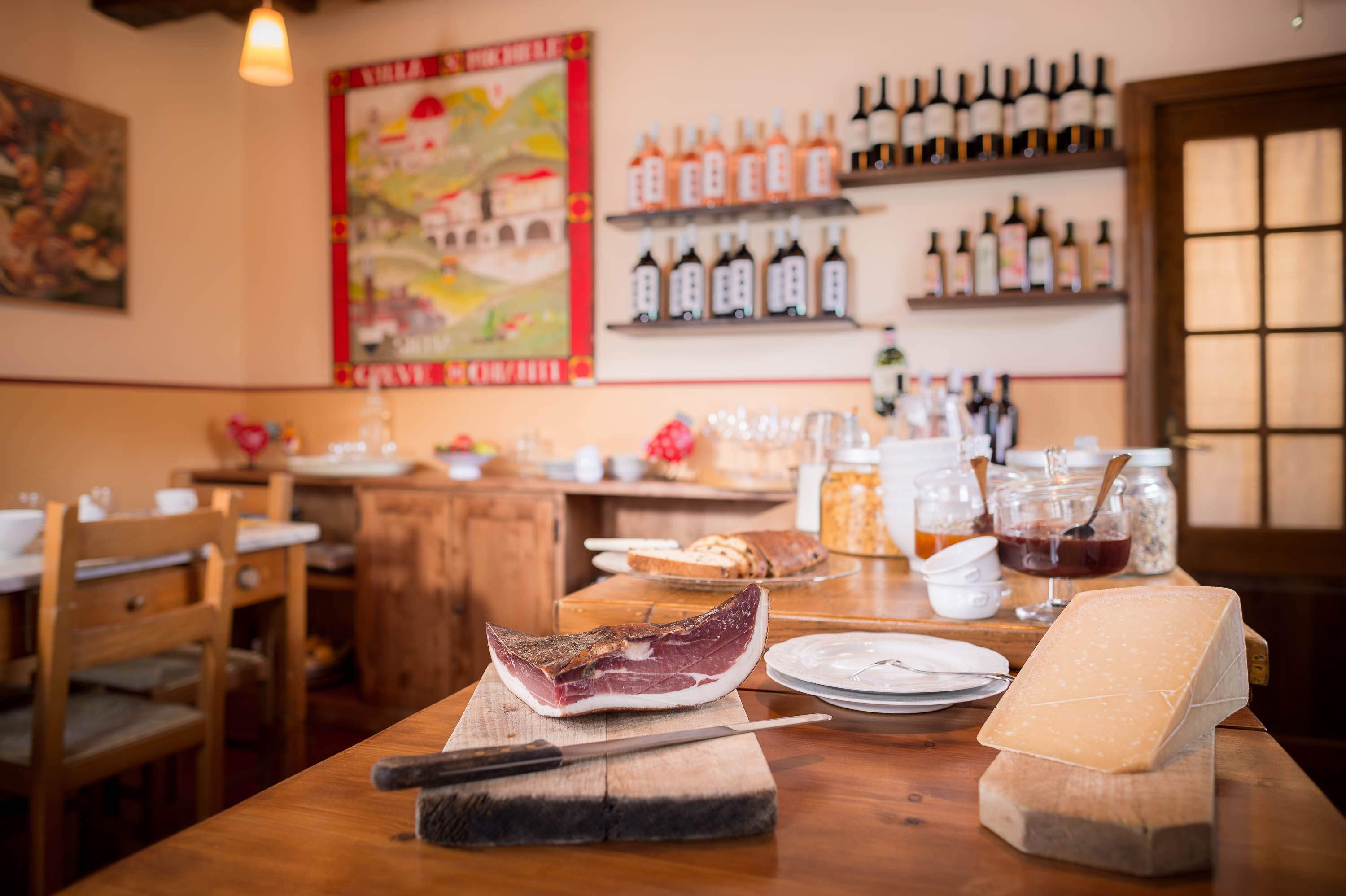 A restaurant interior with wooden furniture, a variety of cheeses, and wine bottles on shelves.