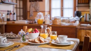 Una mesa de desayuno con un bol de fruta, una jarra de jugo de naranja y una taza de café.