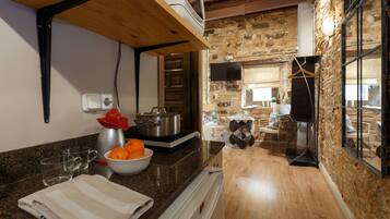 A kitchen with granite countertops, a stove, a sink, and a bowl of oranges.