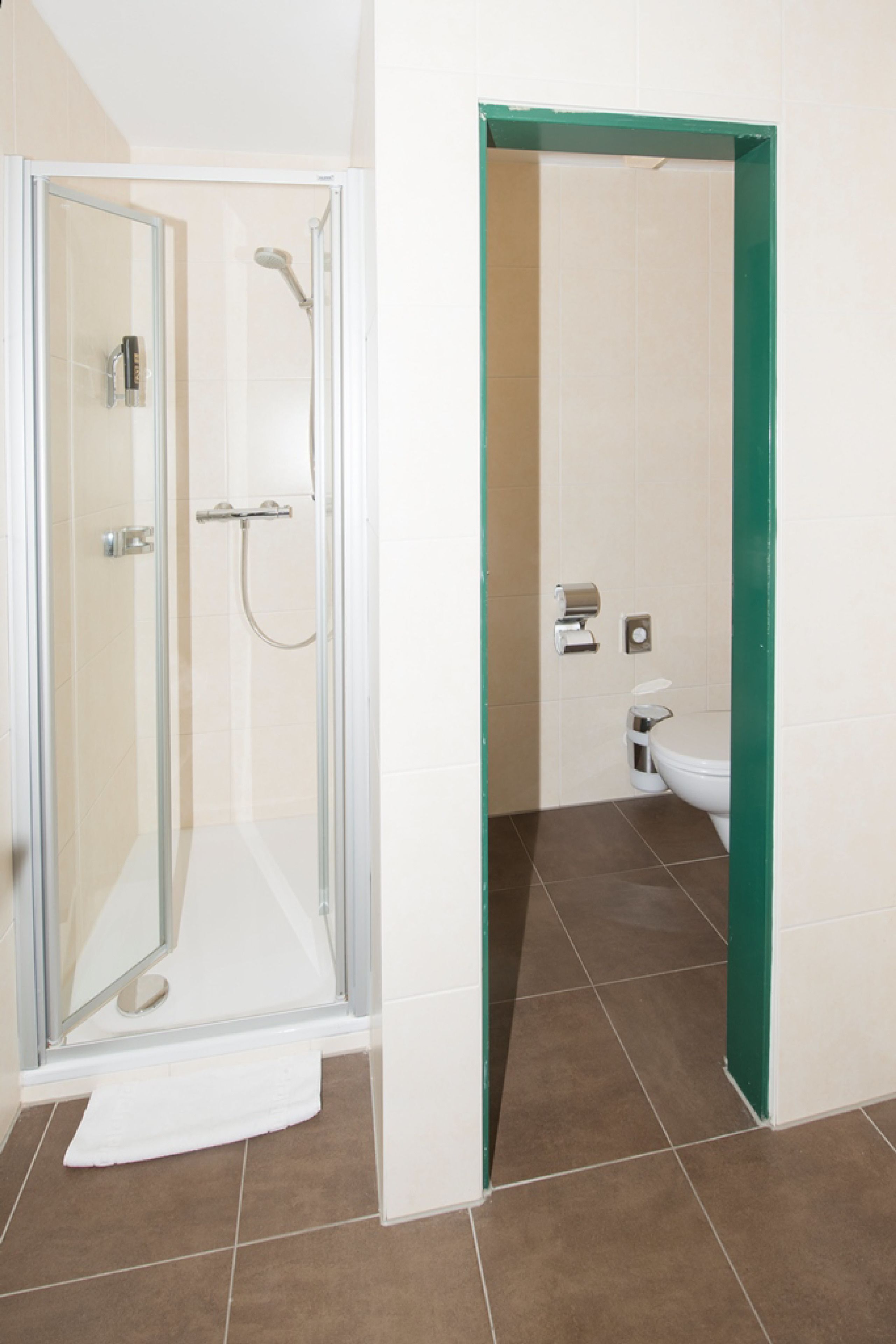 Un baño con cabina de ducha de vidrio, inodoro y lavamanos blanco.
