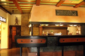 L’intérieur d’un restaurant avec un mur en briques, des poutres en bois au plafond et une enseigne au-dessus du comptoir.