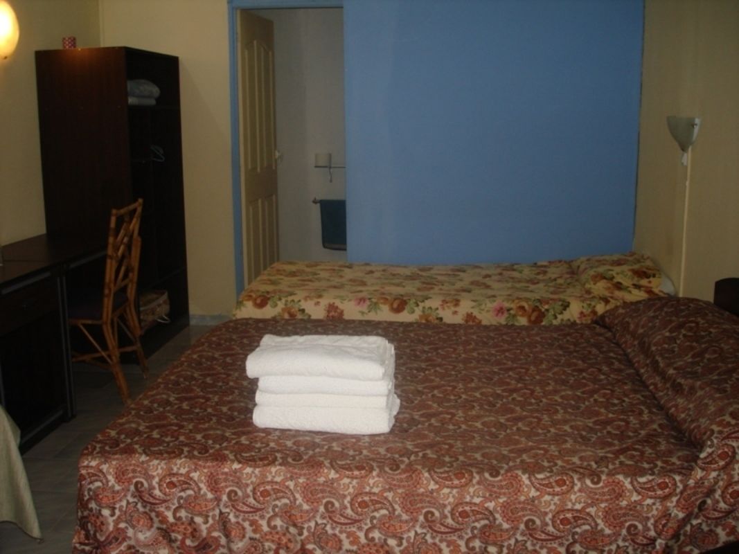 A bedroom with two beds, a wardrobe, a desk, and a chair.