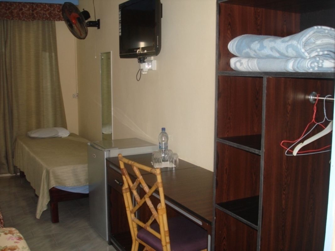 A hotel room with a bed, a desk, a chair, a wardrobe, and a TV.