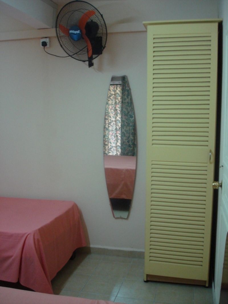 A room with a bed, a wardrobe, a mirror, and a ceiling fan.