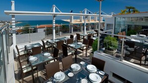 An outdoor dining area with tables set for two, overlooking a coastal view. - Hotel do Cerro (Albufeira)