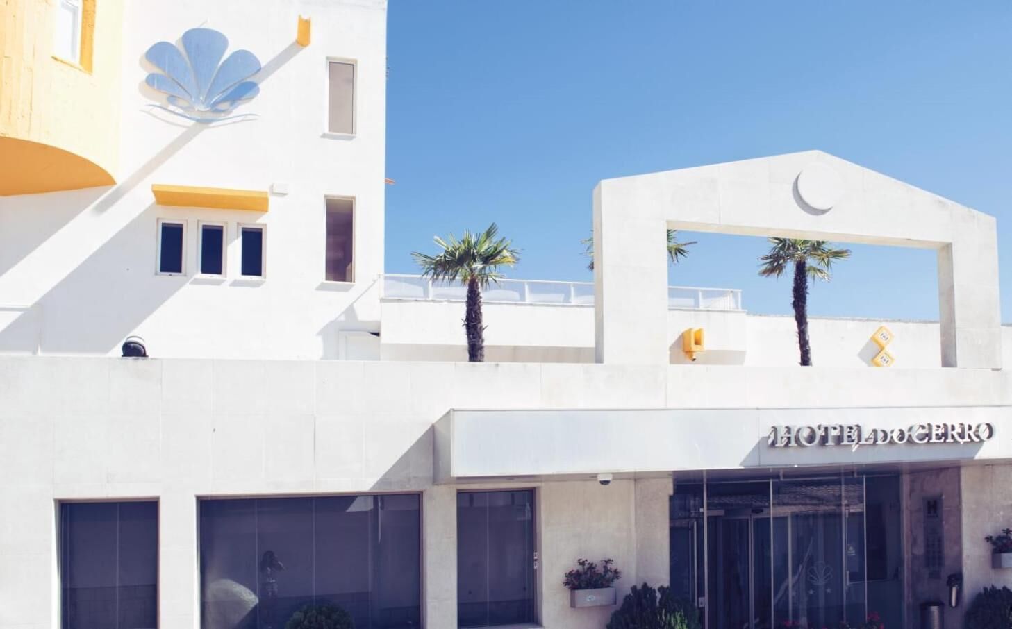 A modern hotel with a prominent crescent moon logo, large glass windows, and a white facade.