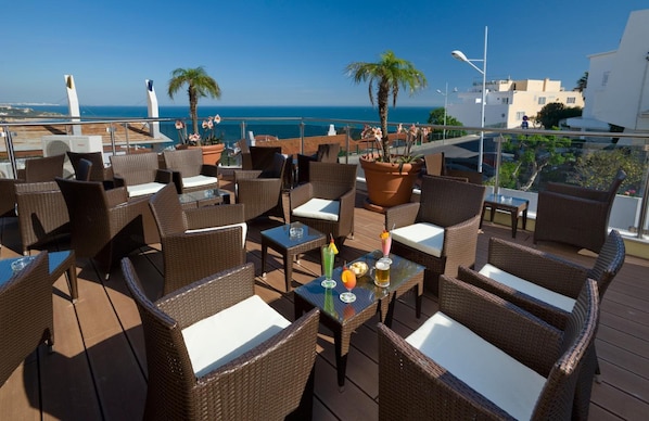 A terrace with wicker furniture and a view of the sea. - Hotel do Cerro (Albufeira)
