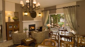 A cozy lounge area with wicker furniture, a fireplace, and a view of the outdoors. - Hotel do Cerro (Albufeira)