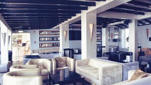 A modern lounge area with sofas and a coffee table, a reception desk, and a patterned wall. - Hotel do Cerro (Albufeira)