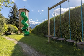 A playground with a green slide and swings. - Hotel - Restaurant Schaurhof (Vipiteno)