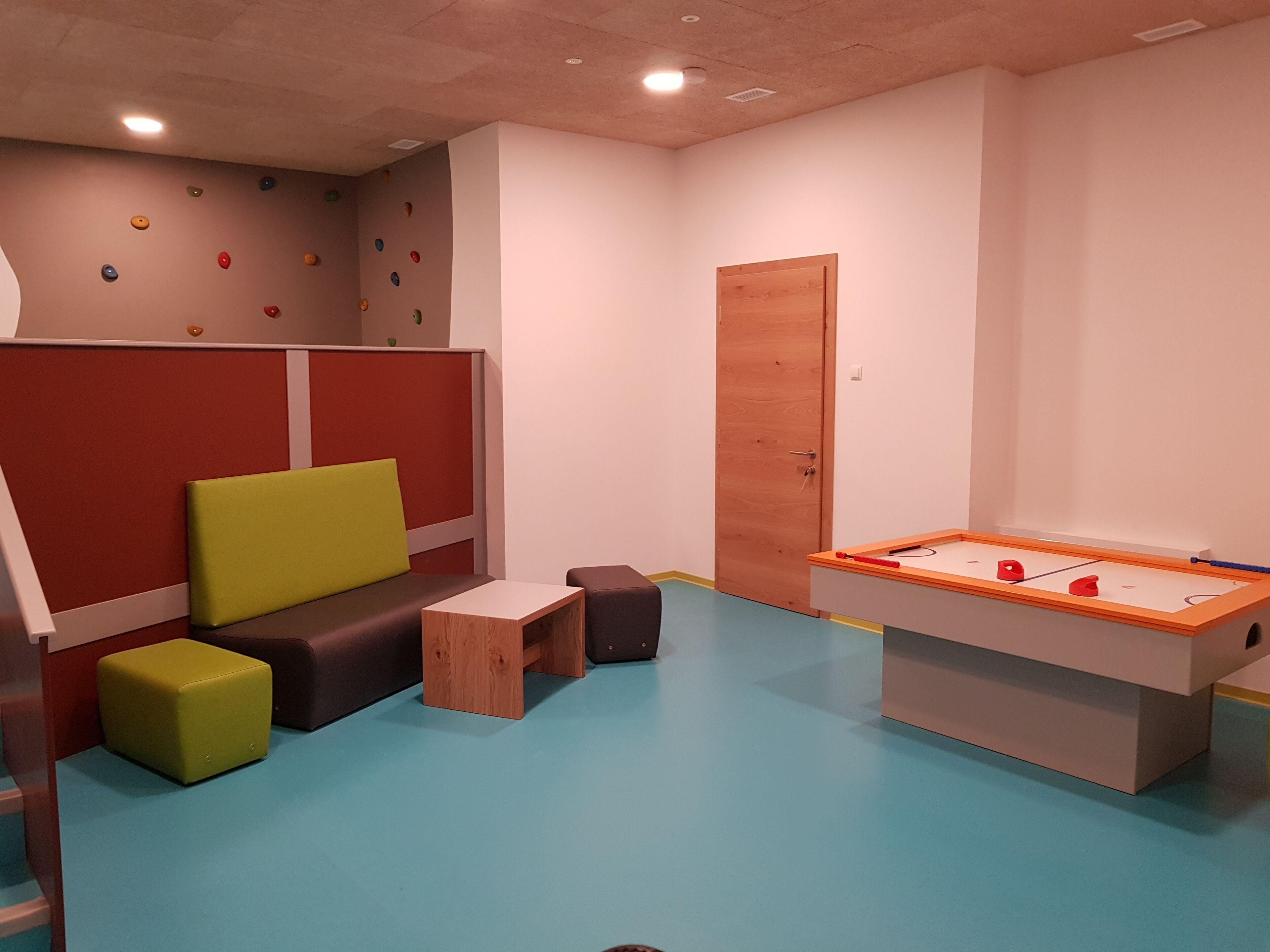 A room with a foosball table, a small table, and a sofa.