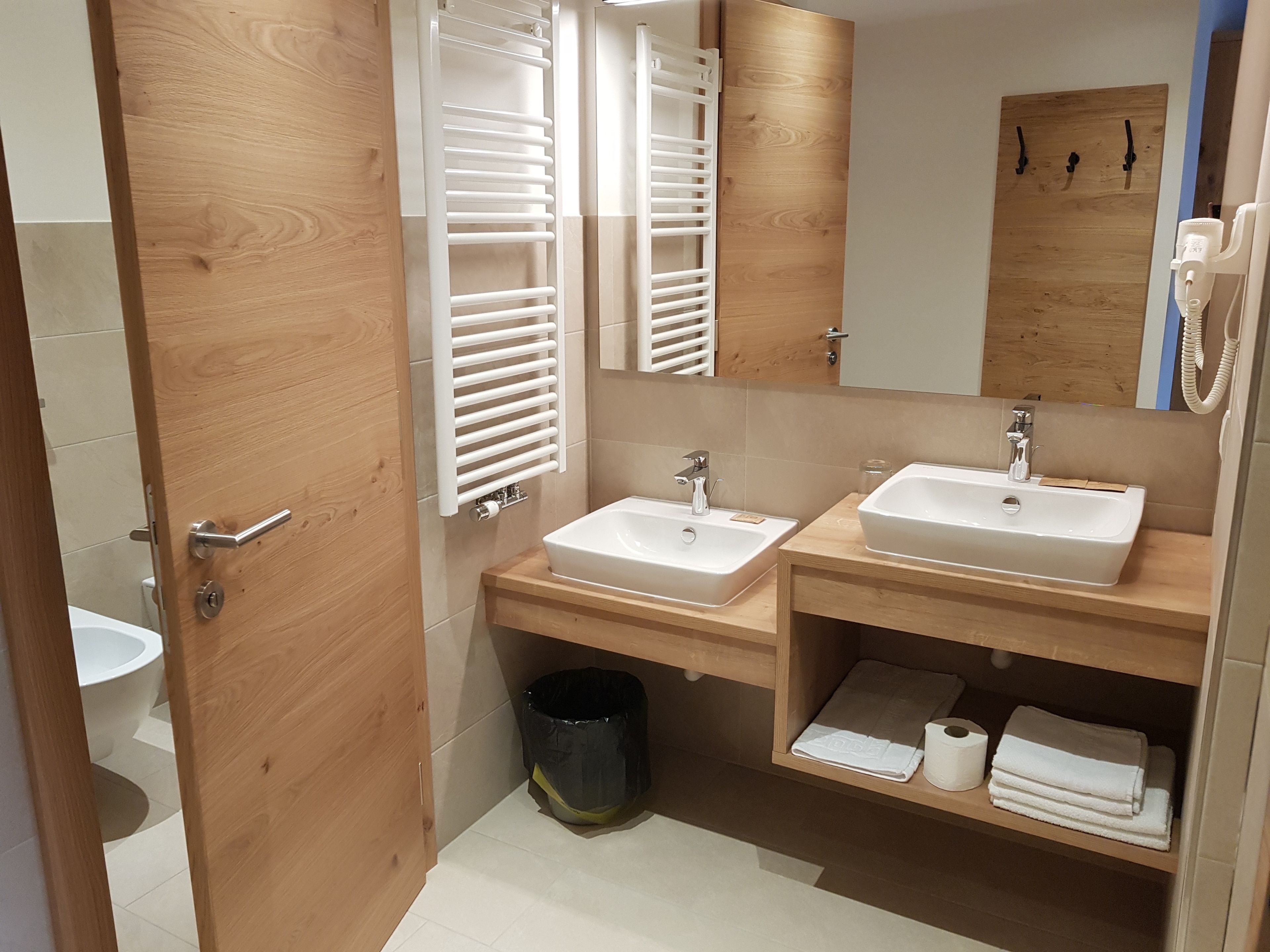 Un baño moderno con dos lavamanos, un espejo y muebles de madera.
