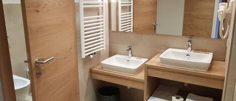 Un baño moderno con dos lavamanos, un espejo y muebles de madera.