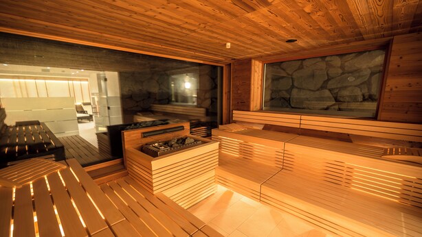 Un sauna avec des bancs en bois et un mur en pierre.
