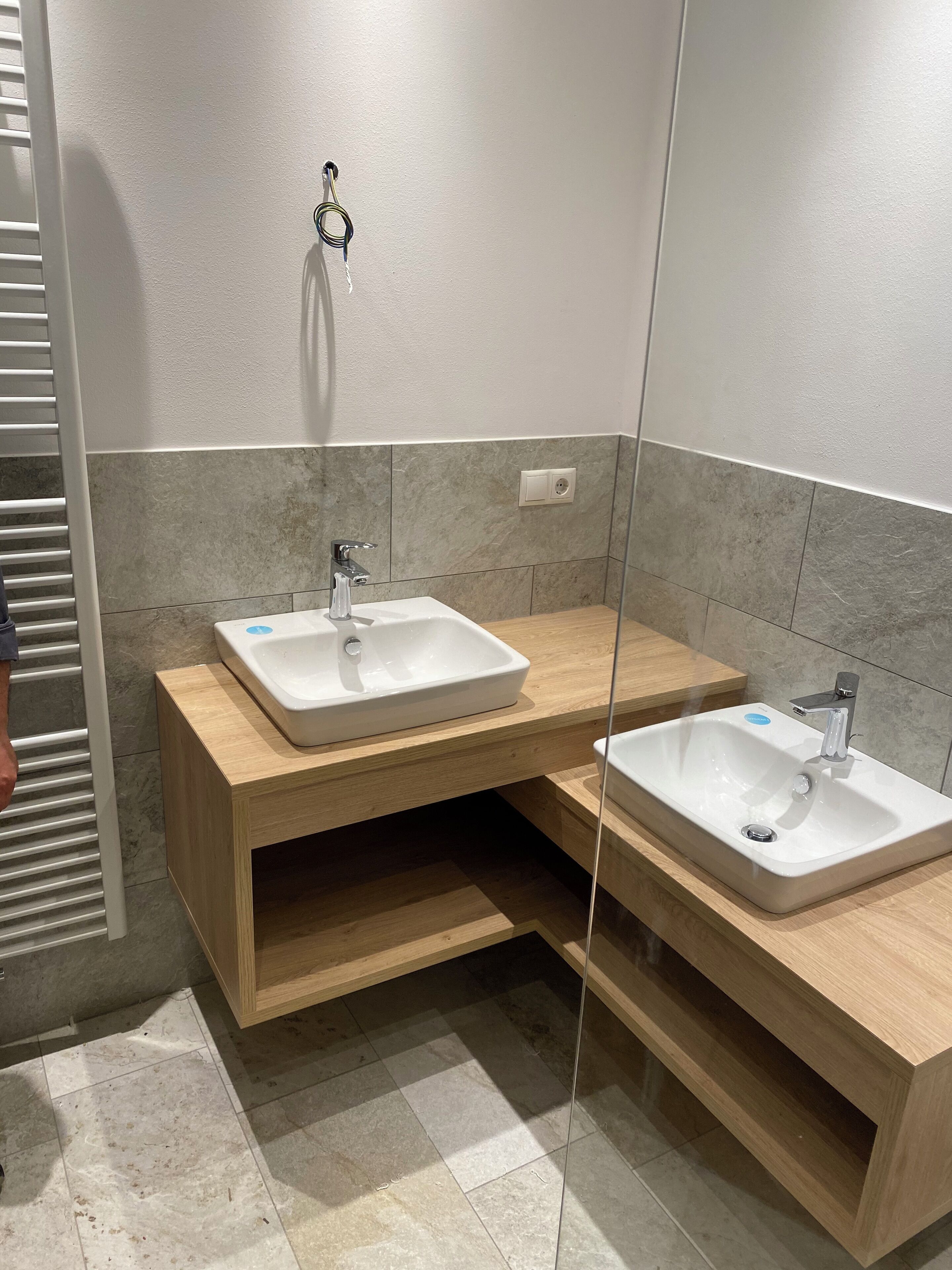 Un baño moderno con dos lavamanos, tocador de madera y paredes con azulejos.