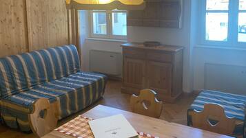 A cozy room with a striped sofa, a wooden dining table with a checkered table runner, and a hanging lamp.