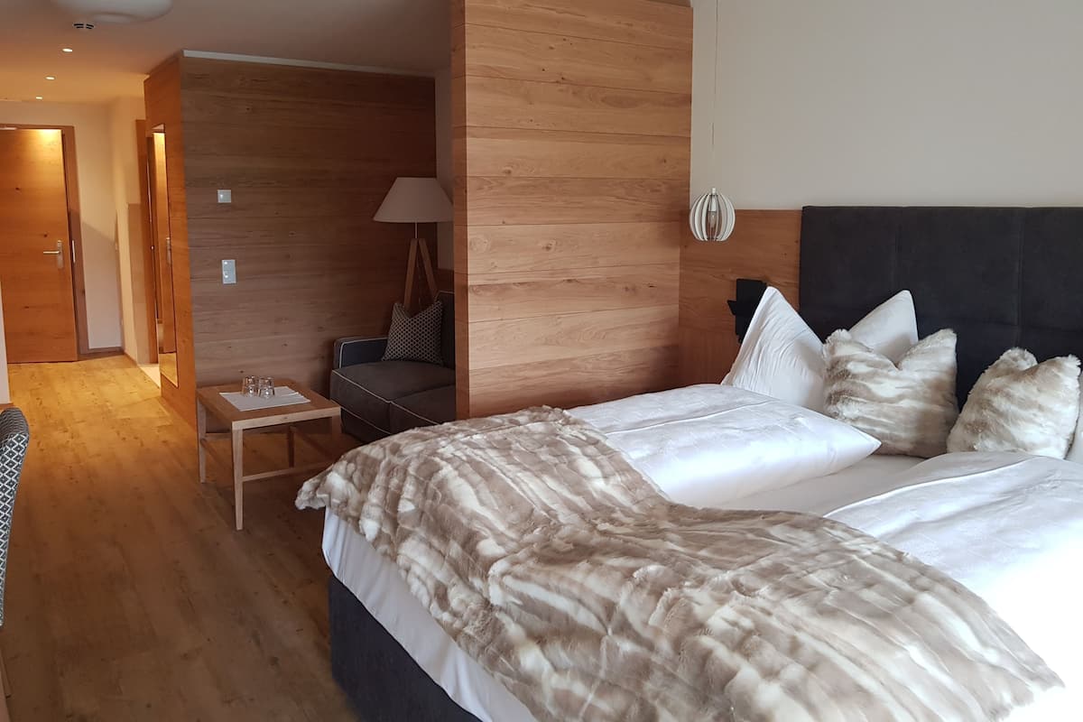 Ein modernes Hotelzimmer mit einem großen Bett, einer Wand mit Holzvertäfelung, einem kleinen Schreibtisch und einem Stuhl.