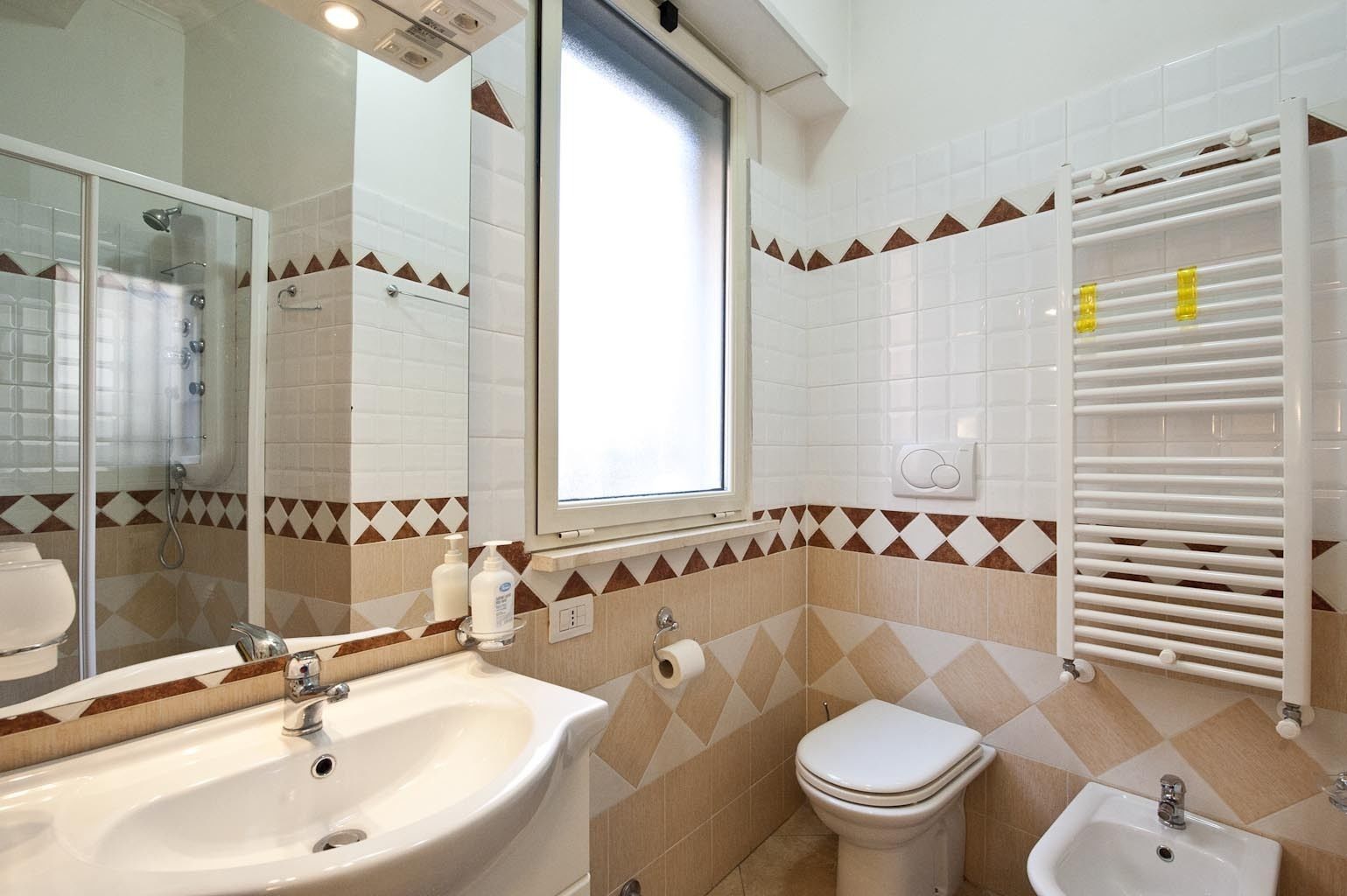 Un bagno con lavandino, WC e bidet. Dispone di finestra, specchio e porta asciugamani.