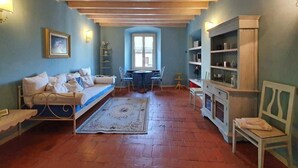 Una habitación acogedora con una cama, una mesita, sillas y una estantería.
