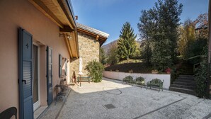 Un patio con paredes de piedra, vigas de madera y mobiliario exterior.