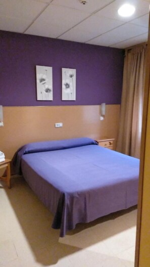 A hotel room with a bed, two wall-mounted light fixtures, and a window with curtains. - Hostal DS (Velilla de San Antonio)