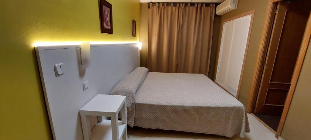 A single bed with a headboard, a bedside table, and a wall-mounted light fixture.